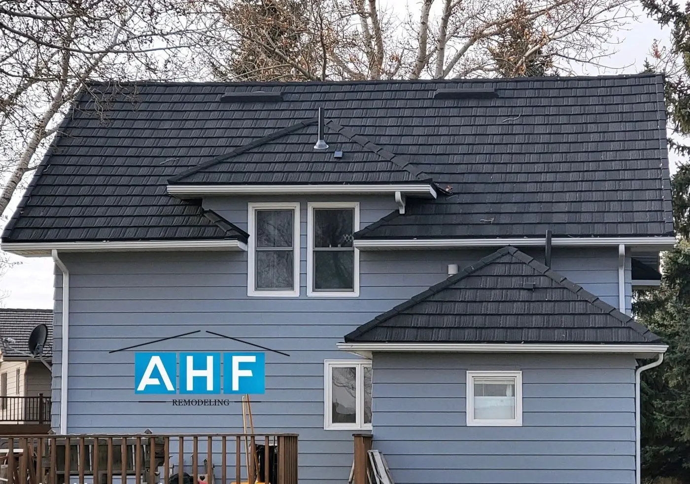 Finished roof replacement on a gray two-story home with an AHF yard sign